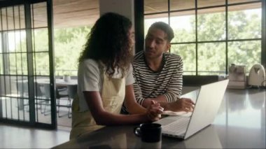 Bir erkek ve bir kadın evdeki bir masada boş bir anı paylaşıyor, pencerenin yanındaki duvarda resim olan bir dizüstü bilgisayara bakıyorlar. Çak!