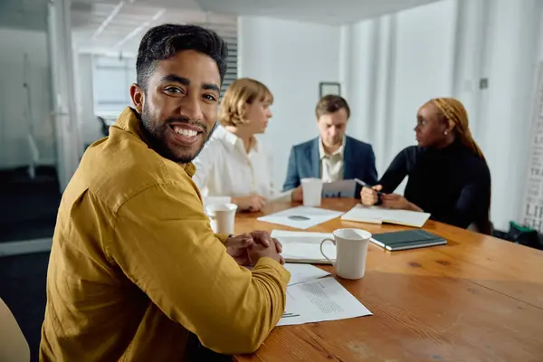 オフィスの会議室で話すビジネスウェアを身に着けている4人の幸せな若い異人種の大人 ロイヤリティフリーのストック写真