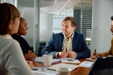 Ofiste dijital tabletle konferans odasında iş kıyafetleri giyen dört genç yetişkin.