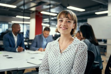 İş hayatında dört yetişkin şirket ofisindeki konferans masasının etrafında sırıtıyor.