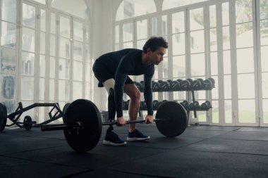 Genç beyaz adam spor salonunda protez bacakla ağırlık antrenmanı yapıyor.