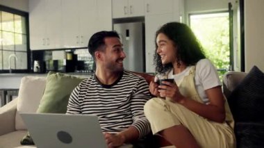 Bir çift kanepede otururken bir dizüstü bilgisayarı paylaşıyor. Adamın parmakları bilgisayarda yazarken kadın gülümsüyor ve kalçasını adamın kalçasına yaslıyor.