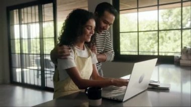 Bir kadın evdeki dizüstü bilgisayarını kullanarak masada oturuyor. Görüntülü arama. Kişisel bilgisayar binanın penceresinin yanındaki masanın üzerine konur.