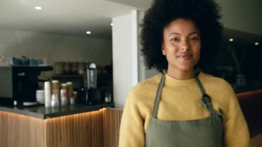 Modern bir kahve dükkanında kollarını kavuştururken gülümseyen kendine güvenen melez bir kahve dükkanı sahibi. Yüksek kalite 4k görüntü