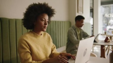 Afrikalı Amerikalı iş kadını, modern bir kahve dükkanında bilgisayarındaki bir e-postaya cevap veriyor. Yüksek kalite 4k görüntü