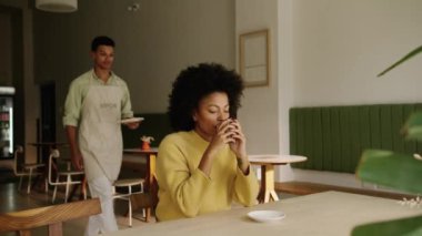 Modern bir kahve dükkanındaki melez bir garsondan kruvasan alan Afrikalı Amerikalı bir müşteri. Yüksek kalite 4k görüntü