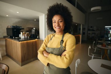 Modern bir kahve dükkanında kolları çapraz duran Afrikalı bir garson. Yüksek kalite fotoğraf