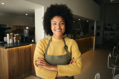 Modern bir restoranda kollarını kavuşturmuş gülümseyen Afrikalı Amerikalı bir barista. Yüksek kalite fotoğraf
