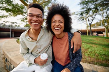 Afrikalı Amerikalı bir adam parkta kolu omzundayken kız arkadaşıyla gülüyor. Yüksek kalite fotoğraf