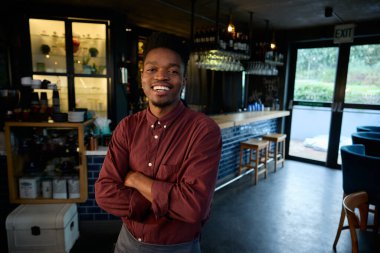 Modern bir restoranda kollarını kavuşturup gülümseyen bir Afrikalı. Yüksek kalite fotoğraf