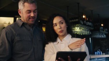 Kafkasyalı bir garson modern bir restoranda iş arkadaşına masa rezervasyonu planını anlatıyor. Yüksek kalite 4k görüntü