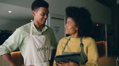 Karışık yarış kahve dükkanları modern bir kahve dükkanındaki tablet üzerindeki bir listeyi kontrol ediyor. Yüksek kalite 4k görüntü