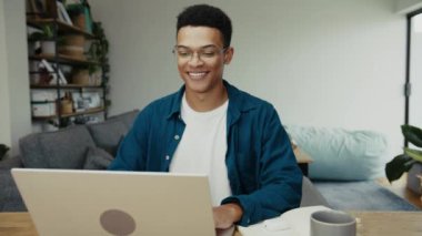 Afrikalı Amerikalı bir üniversite öğrencisi modern bir dairede okul çalışmaları ile ilgili bir video izliyor. Yüksek kalite 4k görüntü