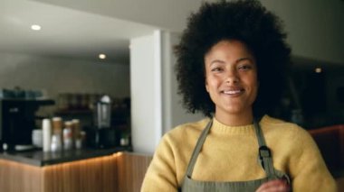 Modern bir kahve dükkanında gülümseyip gülerken kollarını kavuşturan Afrikalı Amerikalı bir kahve dükkanı sahibi. Yüksek kalite 4k görüntü