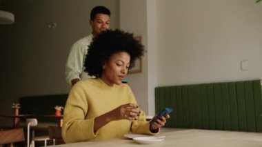 Karışık yarış garsonu, karışık ırktan bir müşteriye modern bir kafede ödemenin nasıl yapıldığını anlatıyor. Yüksek kalite 4k görüntü