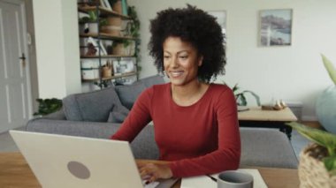 Modern bir dairede dizüstü bilgisayarla çalışan Afrikalı Amerikalı bir girişimci. Yüksek kalite 4k görüntü