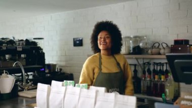 Afro-Amerikalı bir barista, modern bir kahve dükkanındaki müşteriye paket kahve veriyor. Yüksek kalite 4k görüntü