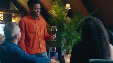 Modern bir restoranda arkadaşlarının doğum günü için kadeh kaldıran Afrikalı bir adam. Yüksek kalite 4k görüntü