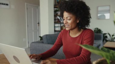 Afrikalı Amerikalı üniversite öğrencisi modern bir dairede bilgisayarda kompozisyon yazıyor. Yüksek kalite 4k görüntü