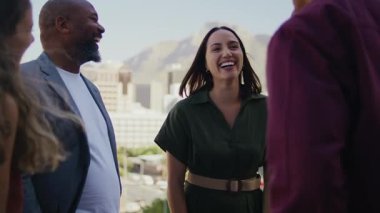 İş kadını iş arkadaşlarıyla birlikte gülerek şehrin çatısına çıkıyor.