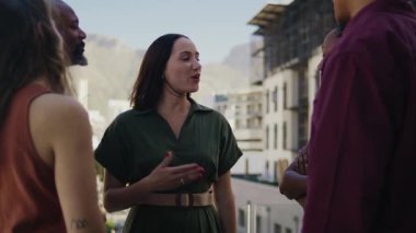 İş kadını, güneşli bir günde çatıdaki terasta çeşitli meslektaşlarıyla konuşuyor.