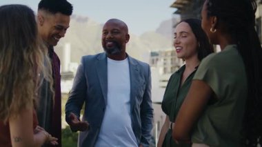 Olgun siyah işadamı, gündüz vakti çatıdaki terasta çeşitli takımlarla tartışıyor.