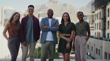 Güneşli bir günde modern şehrin çatısında bir araya gelen çeşitli gülümseyen iş adamları.