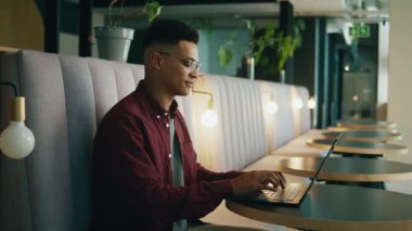 Modern ofis salonunda dizüstü bilgisayar kullanan akıllı, genç bir iş adamı.