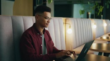 Modern ofis salonunda dizüstü bilgisayarla çalışan akıllı, genç ve yakışıklı bir yönetici.