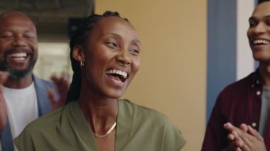 Gündüz vakti modern ofis alanında siyahi iş kadınlarını alkışlayan bir grup farklı iş arkadaşı