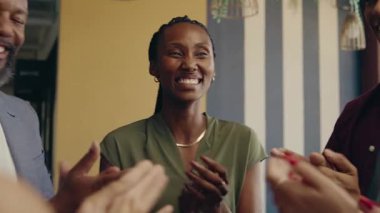 Çeşitli iş arkadaşları modern ofis ortamında gülen iş kadınlarını alkışlıyorlar.