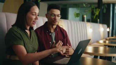 Modern ofis salonunda otururken bilgisayarla tartışan zeki iş arkadaşları.