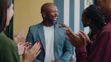 Gündüz vakti modern ofis alanında siyahi işadamını alkışlayan bir grup farklı iş arkadaşı