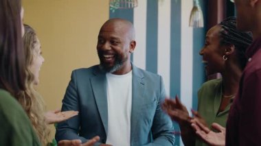 Gündüz vakti modern ofis alanında siyahi iş adamını alkışlayan çeşitli meslektaşlar grubu