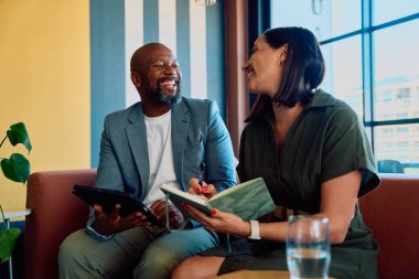 Modern ofis salonunda bayan meslektaşımla konuşurken neşeli iş adamı tablet tutuyordu.