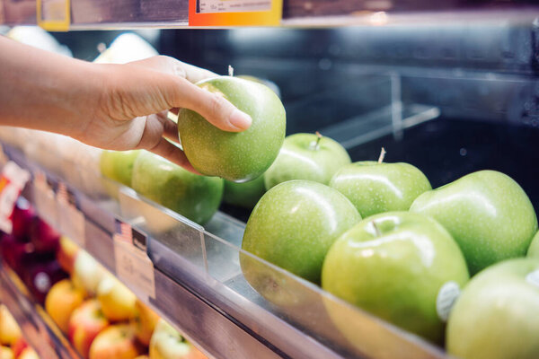 человек, выбирающий яблоко в витрине в продуктовом магазине, органическом образе жизни и веганской концепции.