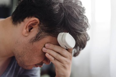 Baş ağrısı olan, parmak ucu nabız ölçer, tıbbi izleme ve ev sağlığı konsepti olan bir adam..