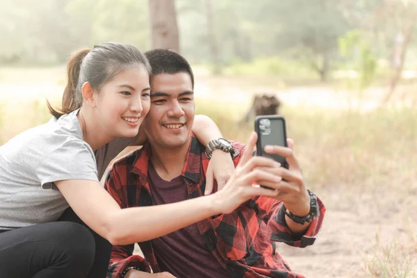 Asyalı genç bir çift akıllı telefonuyla selfie çekiyor..