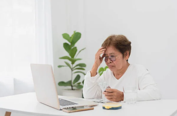 远程医疗和家庭医疗的概念 亚洲老年妇女的担忧以及与医生在家里带笔记本电脑的桌旁举行的视频会议 — 图库照片
