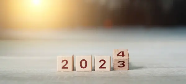 Bu görüntü değişim konseptini yakalar ve yeni yıl 2024 'te yeni bir başlangıç yapar. Görüntü, üzerinde 2023 ve 2024 rakamları bulunan tahta bloklar içeriyor ve bu da yeni yıla geçişi simgeliyor..