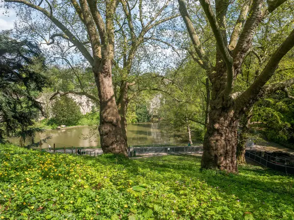 stock image Paris, France - April, 15, 2022: The Parc  des Buttes Chaumont, landscape view depicting its nature, green grass with some people profiting a holiday