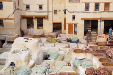 Fes, Morocco - October 11, 2015: a traditional tannery at Fes, depicting the tanning process with a few people  working clipart