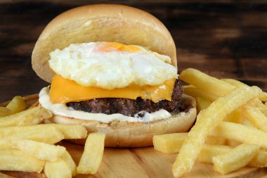 Hamburgerli biftek salata soğan ve peynirli fast food ahşap masaya izole edilmiş.