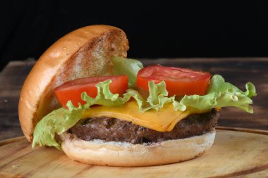 Hamburgerli biftek salata soğan ve peynirli fast food ahşap masaya izole edilmiş.