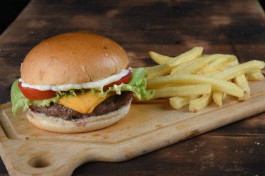 Hamburgerli biftek salata soğan ve peynirli fast food ahşap masaya izole edilmiş.