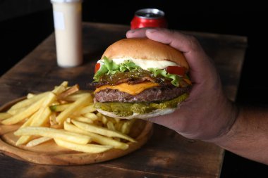 Hamburgerli biftek salata soğan ve peynirli fast food ahşap masaya izole edilmiş.