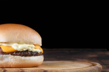 Pastırmalı burger sandviçi, salata, yumuşak yumurta ekmeği, siyah arka planda izole edilmiş ahşap masa.