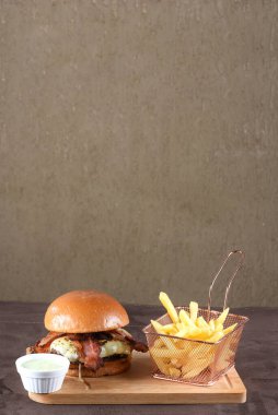 Lezzetli sığır burger, sandviç, salata, soğan ve peynirli fast food. Tahta masa yemeğinden izole edilmiş.