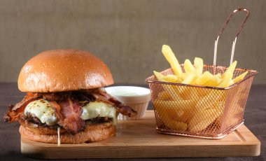 Lezzetli sığır burger, sandviç, salata, soğan ve peynirli fast food. Tahta masa yemeğinden izole edilmiş.