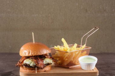 Lezzetli sığır burger, sandviç, salata, soğan ve peynirli fast food. Tahta masa yemeğinden izole edilmiş.